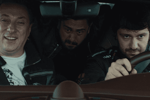 Three men sitting in a car, two of them look excited about the high speed and the other one looks scared