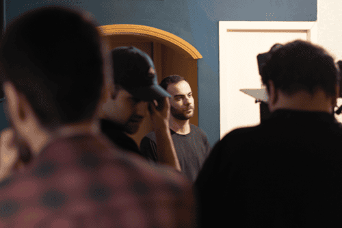 Behind the scenes of Withered Pomegranates with director Moein Rahmanzadeh and lead actor Behrad Selahvarzi; and Shahab Malekpoor and Sahand Khalaj Moein standing and directing the others.